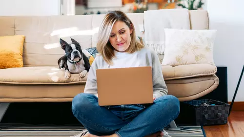 En kvinna sitter i sitt vardagsrum och gör en budgetkalkyl på sin laptop