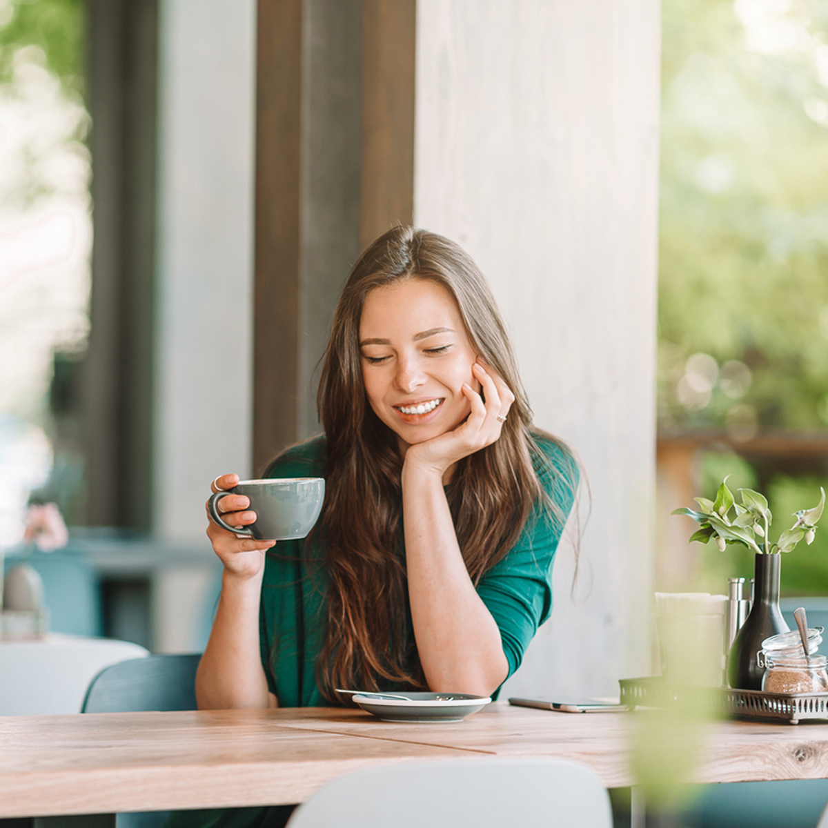 En kvinna sitter vid ett  cafébord och dricker kaffe.