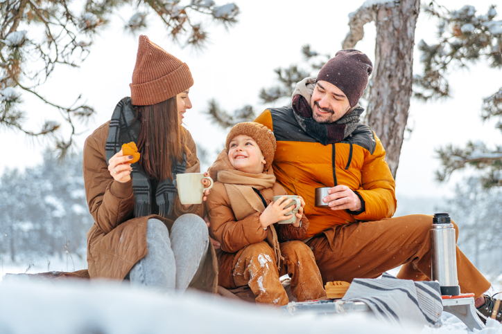 Familj äter picknick ute i snön