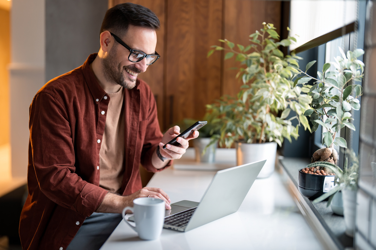 Man kollar på sin mobil och laptop