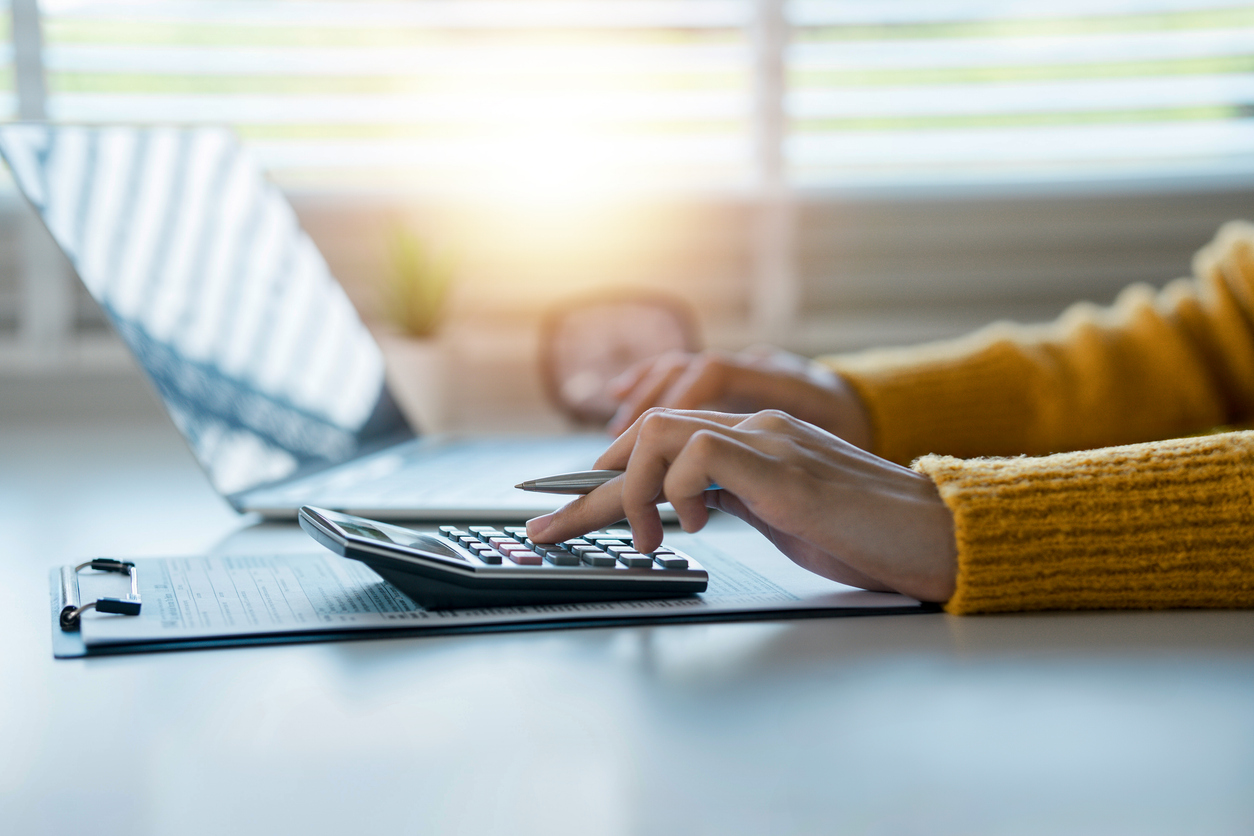 Person sitter vid en miniräknare och dator