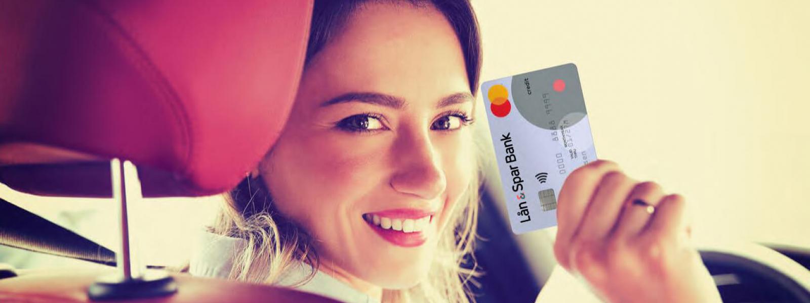 Tjej sitter i bilen och visar sitt Lån & Spar Bank Mastercard