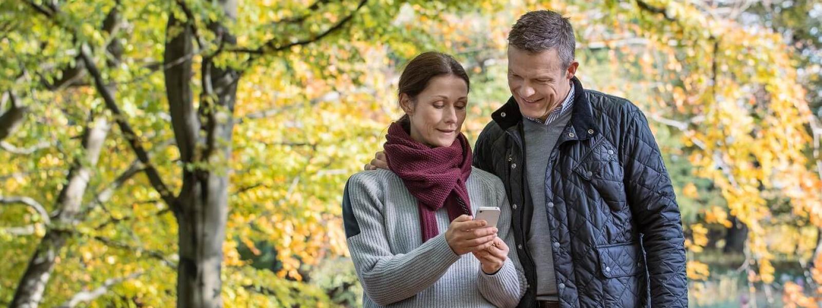 Par kollar på sin mobil ute i skogen
