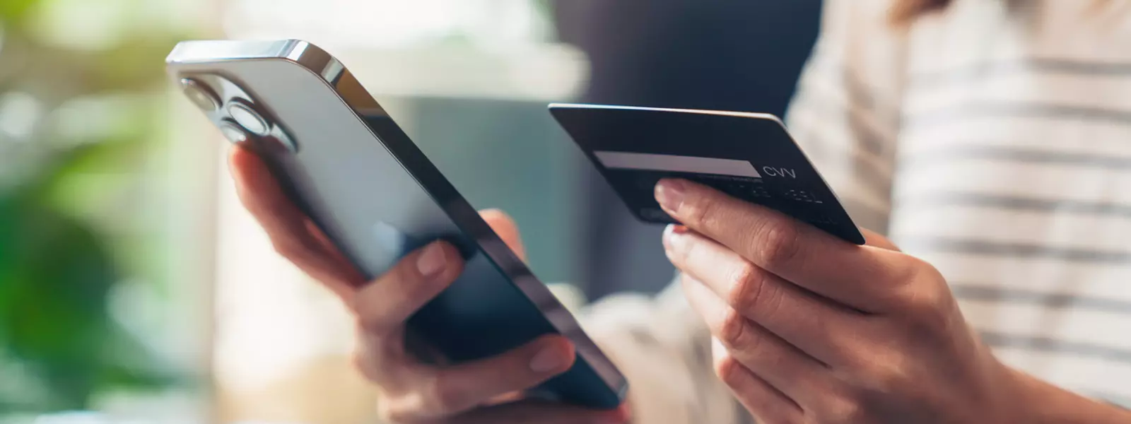 Kvinna som sitter med mobilen och sitt kreditkort