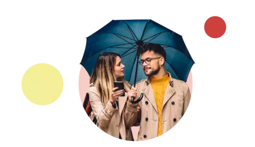 Ett par står under sitt paraply och kollar på en mobiltelefon