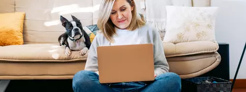 En kvinna sitter i sitt vardagsrum och gör en budgetkalkyl på sin laptop