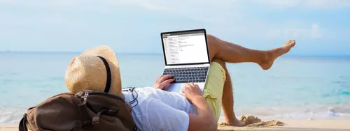 Man sitter vid sin dator på stranden