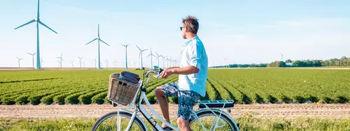 Man cyklar och vindkraftverk är i bakgrunden