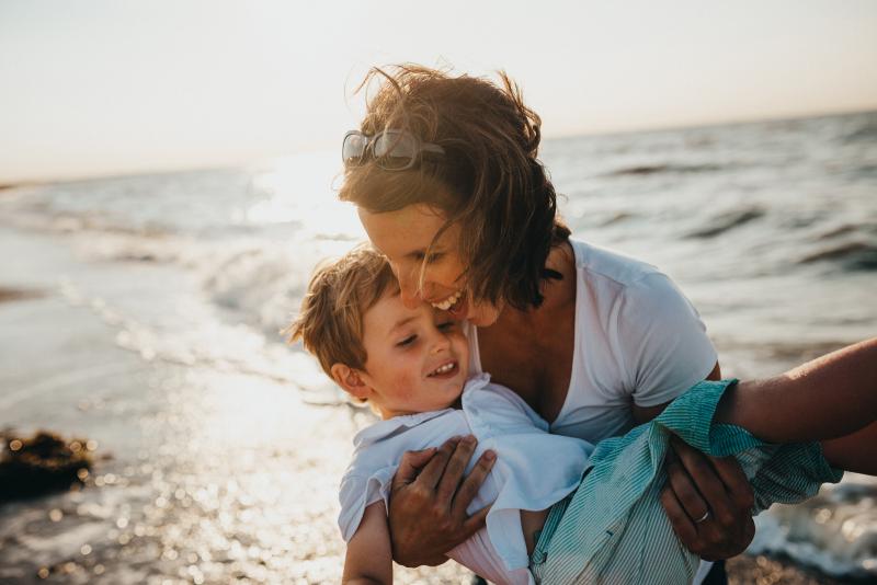 Mamma lyfter sin son på stranden