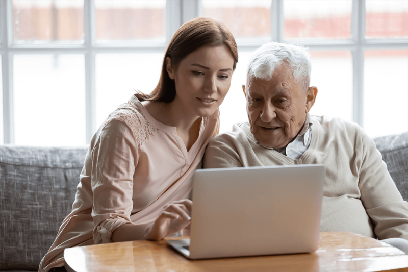En kvinna hjälper en äldre herre med ett datorärende