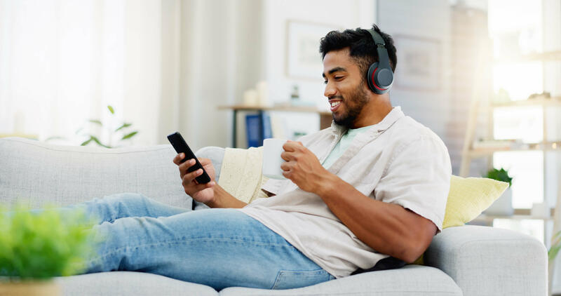 En kille läser på mobilen och lyssnar på en podcast