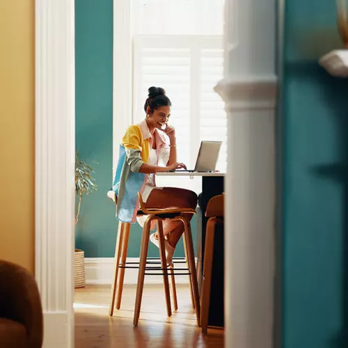 En kvinna sitter vid ett bord med sin dator.