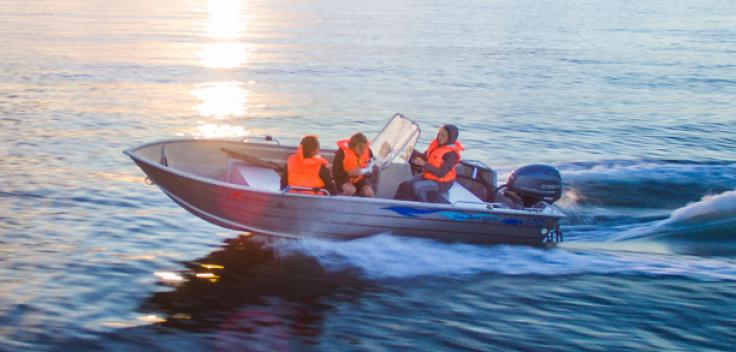 Tre personer åker i en lite båt på havet
