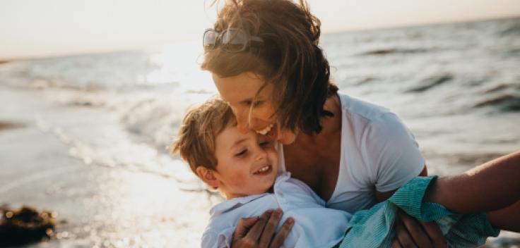 Mamma lyfter sin son på stranden