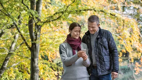 Par kollar på sin mobil ute i skogen