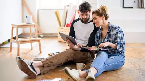 Ett par, en man och kvinna, sitter och planerar renovering på golvet