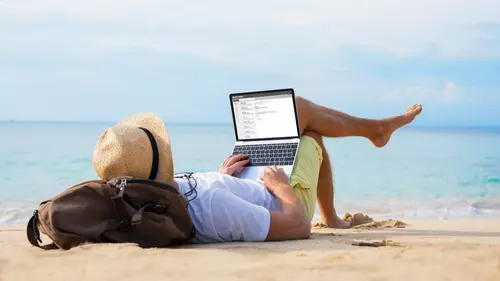 Man sitter vid sin dator på stranden