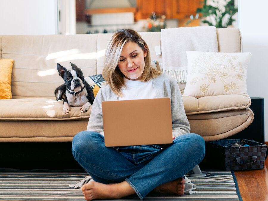 En kvinna sitter i sitt vardagsrum och gör en budgetkalkyl på sin laptop