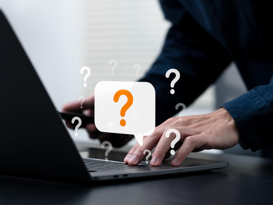 Person skriver på datorn och animerade frågetecken runtom