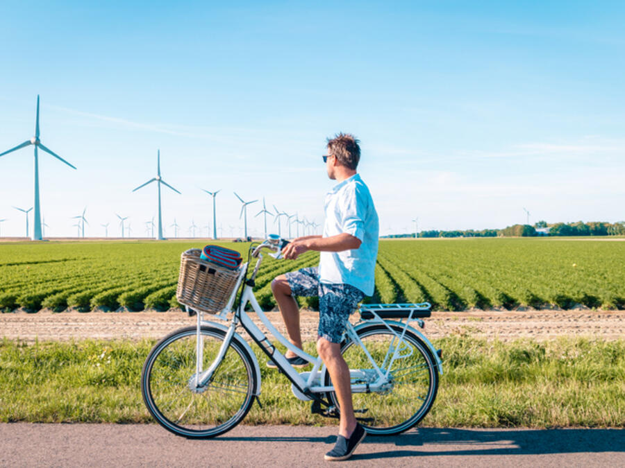 Man cyklar och vindkraftverk är i bakgrunden